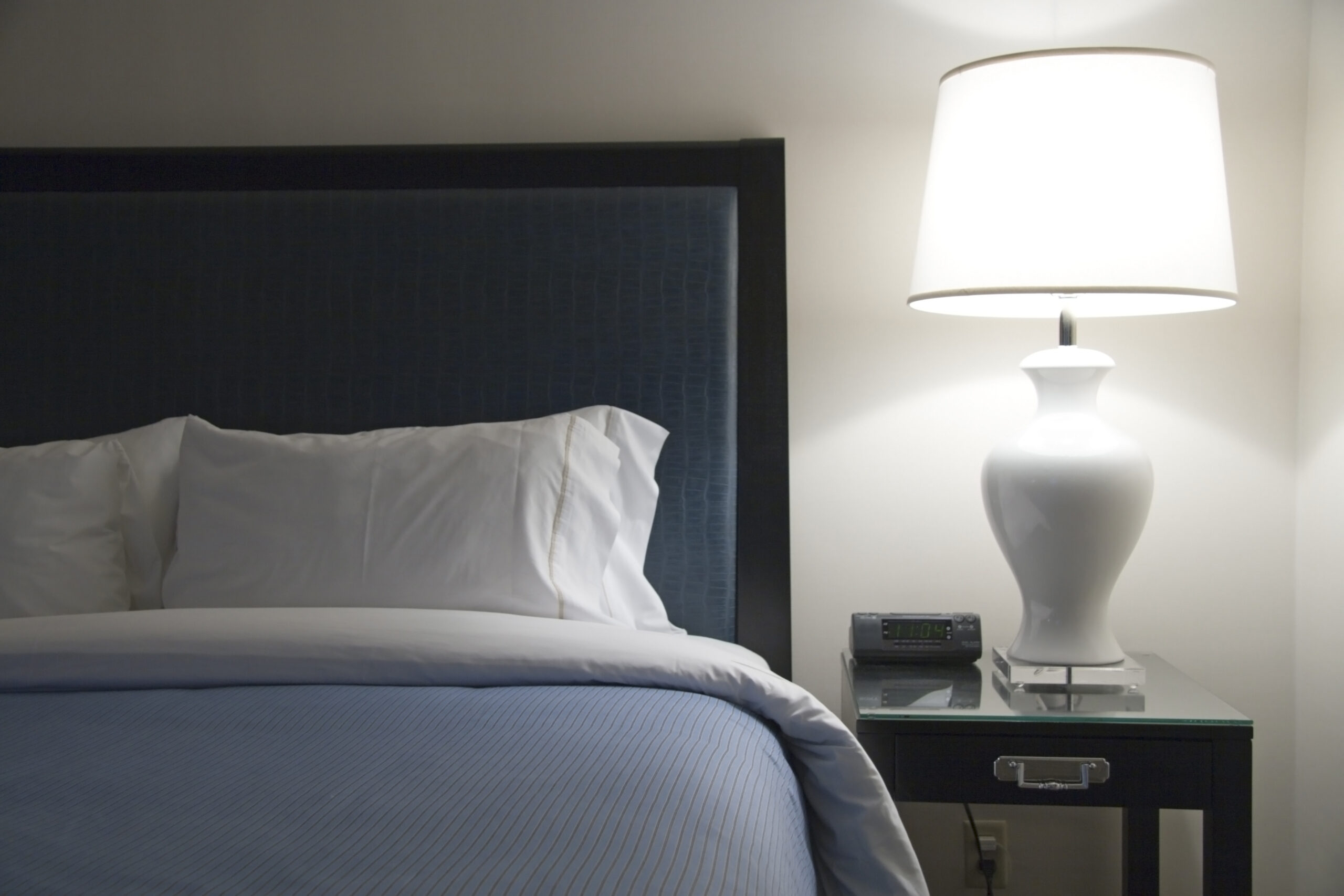 Bed of modern hotel with blue accents next to a lot lamp