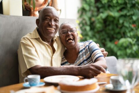 A senior couple laughs through breakfast.