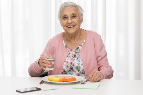 A senior woman enjoys her meal.