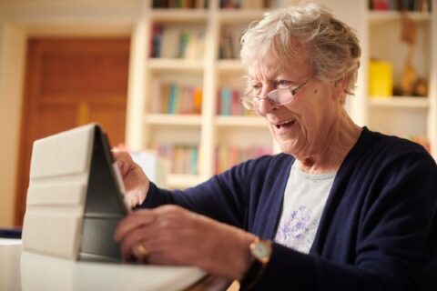 A senior woman connects with friends on her tablet.