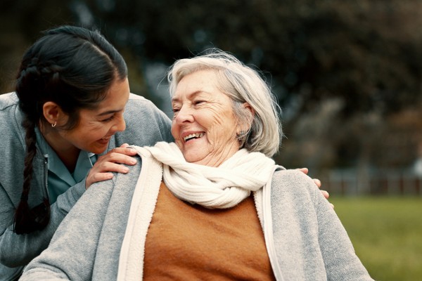 Caregiver helping woman with disability in park for support, trust and care in retirement.