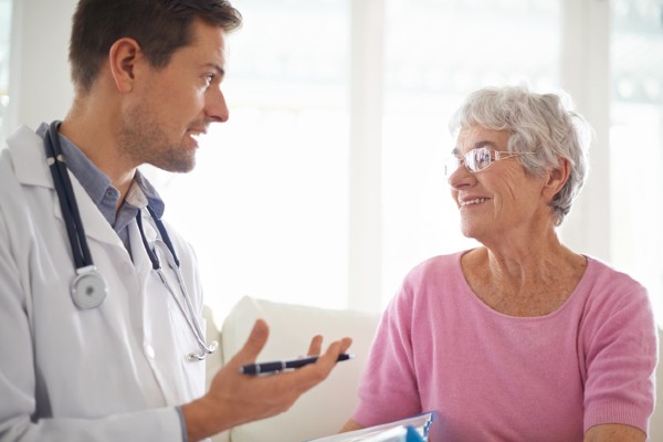 A female senior talks to her doctor in his office.