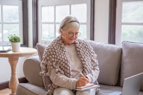 A senior woman in a shawl journals.